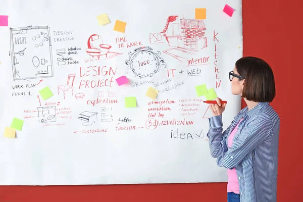 Female designer near big paper sheet with project plan in office — Stock Photo, Image