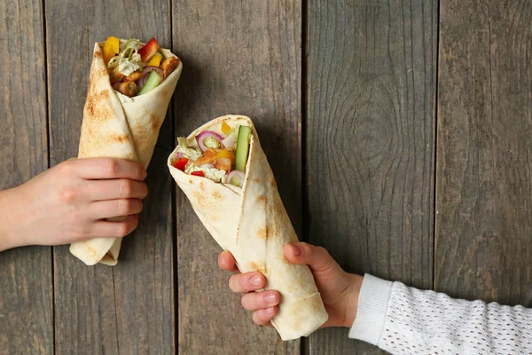 Female hands with tasty doner kebab on wooden background — Stock Photo, Image