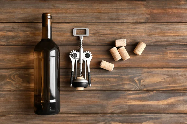 Bottle of wine with corkscrew on wooden table — Stock Photo, Image