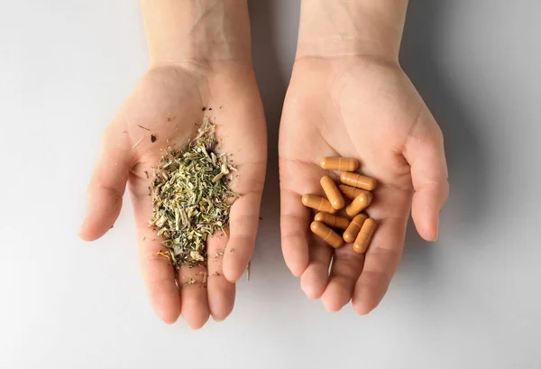 Női kéz a növényi alapú tabletták és száraz gyógynövények, fehér háttér — Stock Fotó