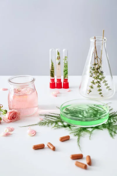 Скляний посуд з інгредієнтами для приготування таблеток на основі рослин на білому столі — стокове фото