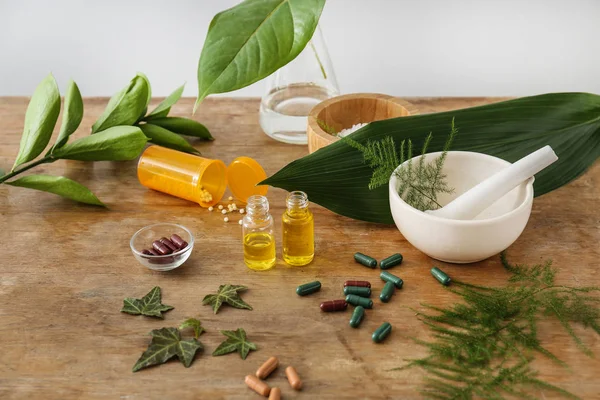 Plant based pills and essential oil on wooden table