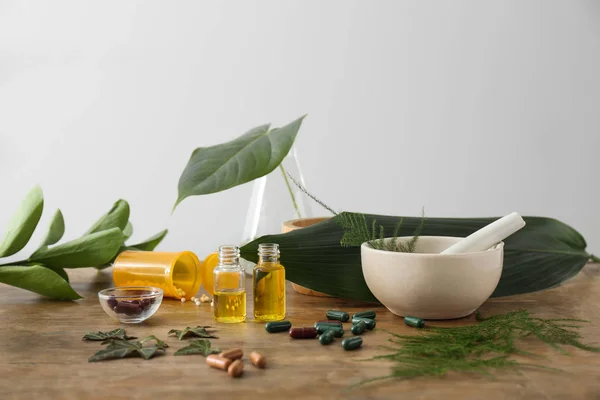 Plant based pills and essential oil on wooden table — Stock Photo, Image