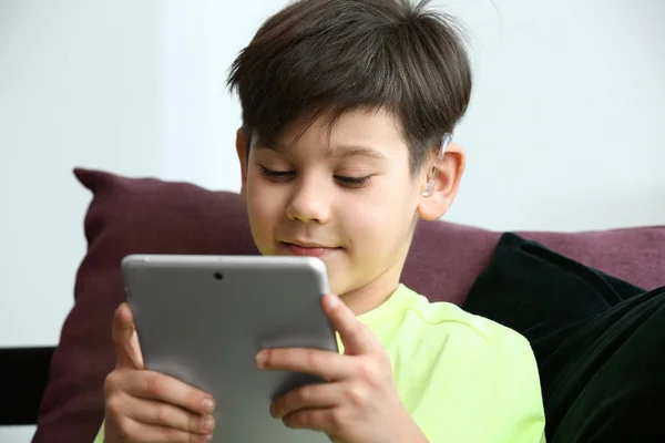 Niño pequeño con audífono usando tableta en casa — Foto de Stock