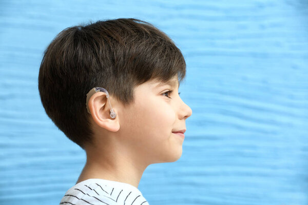 Мальчик со слуховым аппаратом на цветном фоне
