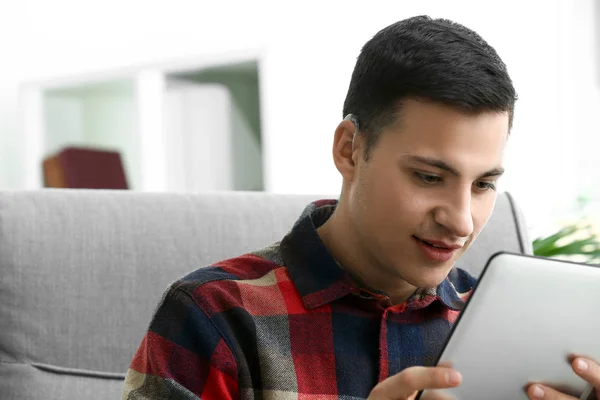 Young man with hearing aid using tablet computer at home — Stock Photo, Image