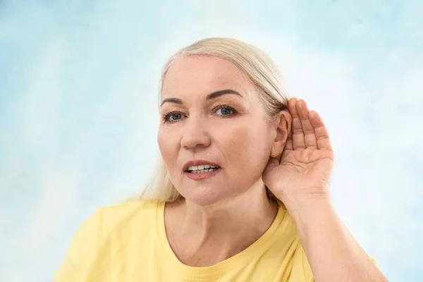 Mature woman with hearing problem on light background — Stock Photo, Image