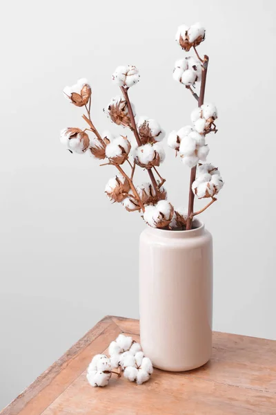 Vase with cotton branches on table against light background — Stock Photo, Image
