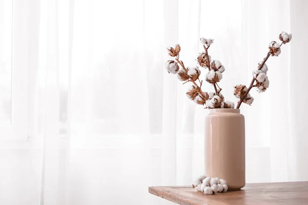 Jarrón con ramas de algodón en la mesa cerca de la ventana — Foto de Stock