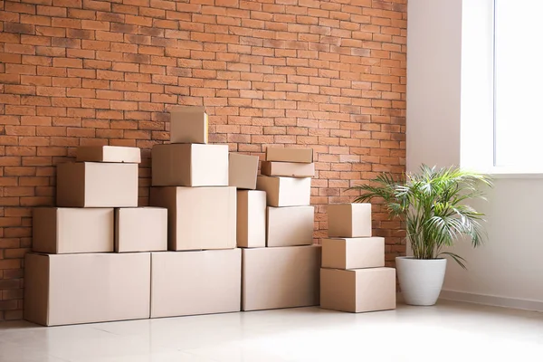 Mover cajas cerca de la pared de ladrillo en la habitación —  Fotos de Stock