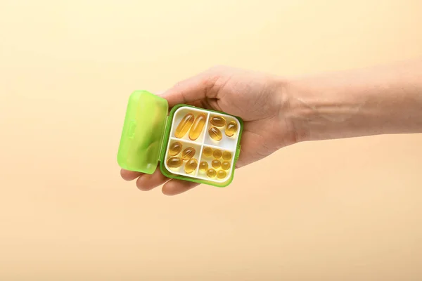 Female hand holding container with pills on color background — Stock Photo, Image