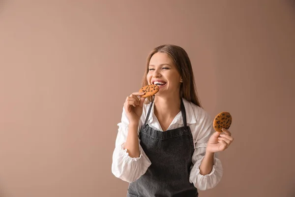 Padeiro fêmea feliz com biscoitos saborosos no fundo de cor — Fotografia de Stock