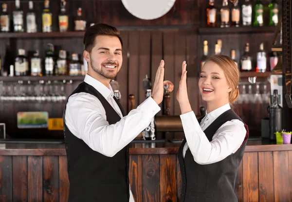 Young waiters giving each other high-five in restaurant — Stock Photo, Image