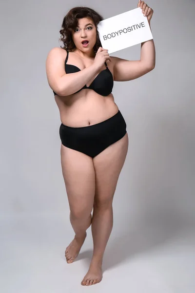Plus size vrouw met papier met tekst Bodypositive op grijze achtergrond — Stockfoto
