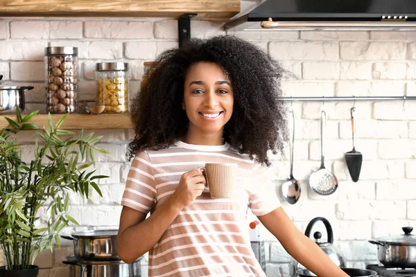 African-American woman drinking coffee in kitchen — Stock Photo, Image