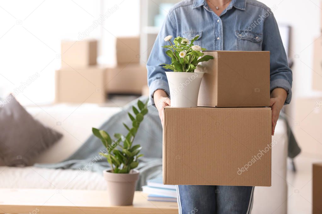 Woman with moving boxes and plant in room