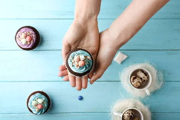 Vrouwelijke handen met smakelijk Pasen cupcakes op houten achtergrondkleur — Stockfoto