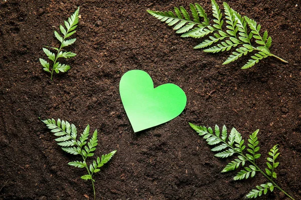 Green heart with leaves on soil. Earth Day celebration