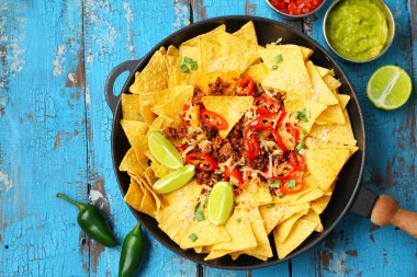 Ahşap masada lezzetli nachos, kıyılmış et ve Chili ile kızartma tavası