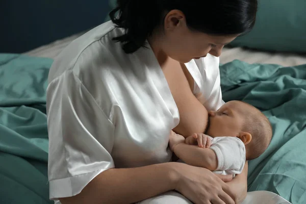 Jovem mulher amamentando seu bebê em casa — Fotografia de Stock