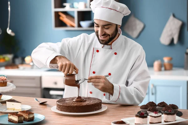 Pastelería masculina decorando sabroso pastel de chocolate en la cocina —  Fotos de Stock