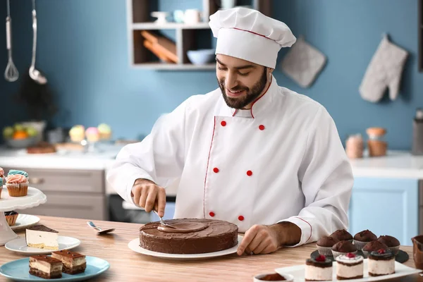 Male confectioner decorating tasty chocolate cake in kitchen — Stock Photo, Image