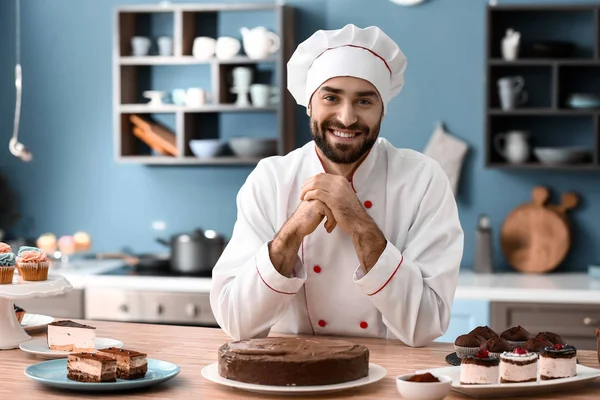 Pastelero masculino con sabroso pastel de chocolate en la cocina —  Fotos de Stock