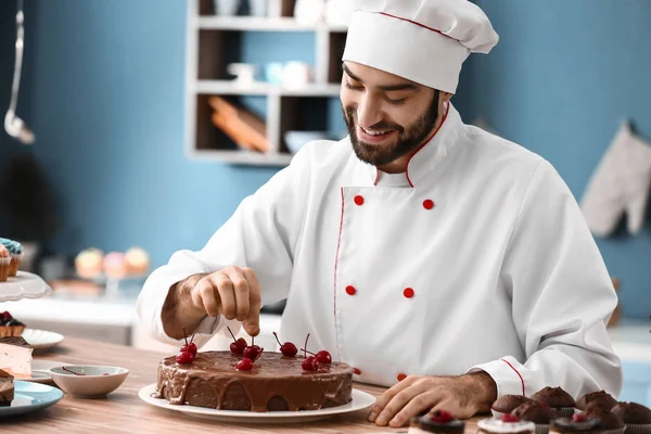 Pastelería masculina decorando sabroso pastel de chocolate en la cocina —  Fotos de Stock