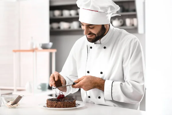 Pastelería masculina decorando sabroso pastel de chocolate en la cocina —  Fotos de Stock