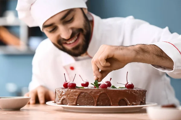 Pastelería masculina decorando sabroso pastel de chocolate en la cocina —  Fotos de Stock