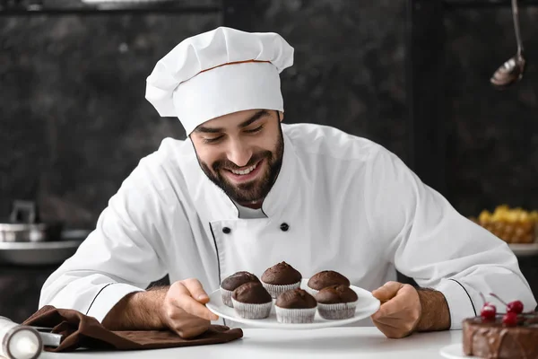 Mužské cukrář s chutné čokoládové muffiny v kuchyni — Stock fotografie