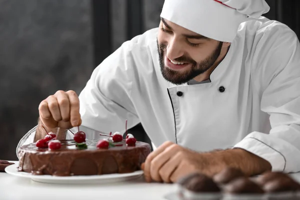 Mužské cukrář zdobení chutné čokoládový dort v kuchyni — Stock fotografie