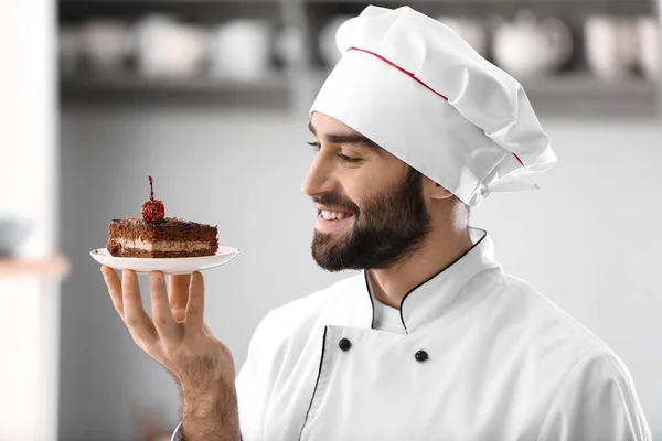 Pastelería masculina con trozo de sabroso pastel de chocolate en la cocina —  Fotos de Stock