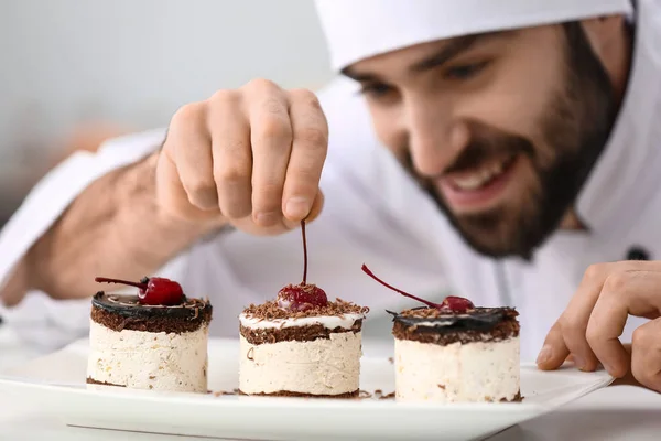 Cukrářský muž zdobující chutný dezert v kuchyni, šatník — Stock fotografie
