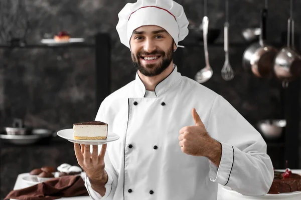 Confeiteiro masculino com pedaço de bolo saboroso na cozinha — Fotografia de Stock