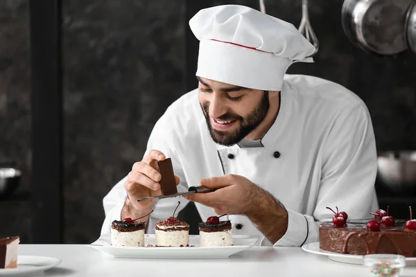 Mannelijke banketbakker versiert smakelijk dessert in de keuken — Stockfoto