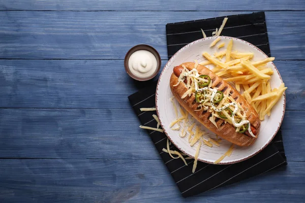 Plate with tasty hot dog on wooden background — Stock Photo, Image