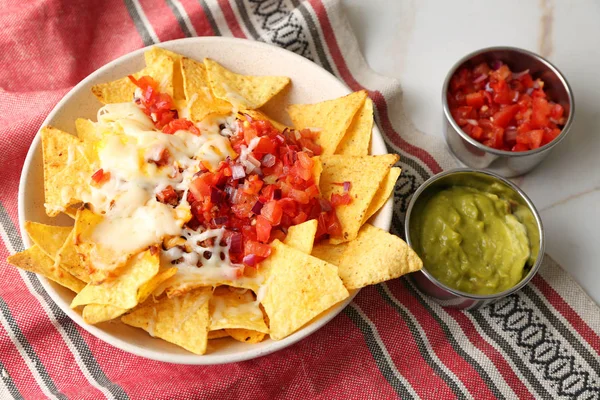 Prato com nachos saborosos, queijo, carne picada e salsa na mesa — Fotografia de Stock