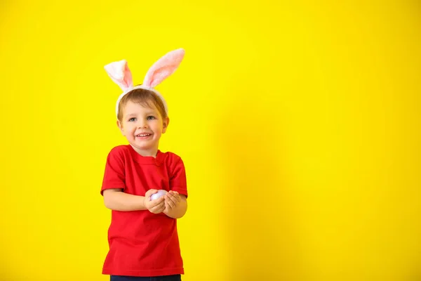可爱的小男孩与复活节彩蛋和兔子耳朵在颜色背景 — 图库照片