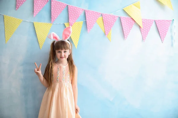 Niedliches kleines Mädchen mit Hasenohren in der Nähe farbig dekorierte Wand — Stockfoto