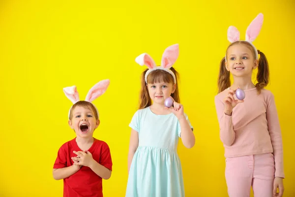 Paskalya yumurtaları ve tavşan kulakları renk arka plan üzerinde küçük sevimli çocukla — Stok fotoğraf