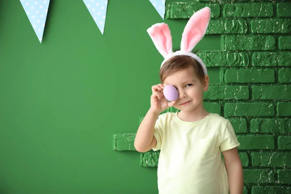 부활절 계란과 컬러 장식 벽 근처 토끼 귀를 가진 귀여운 어린 소년 — 스톡 사진
