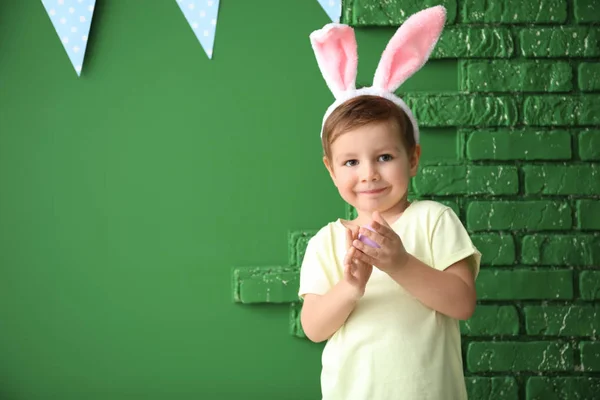 Cute little boy with Easter egg and bunny ears near color decorated wall — Stock Photo, Image