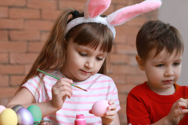 Милые маленькие дети рисуют пасхальные яйца дома
