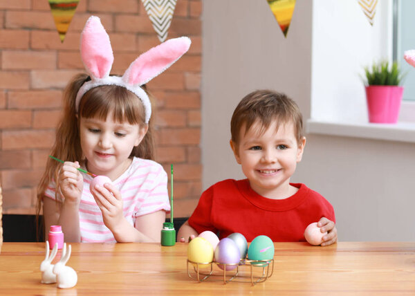 Милые маленькие дети рисуют пасхальные яйца дома
