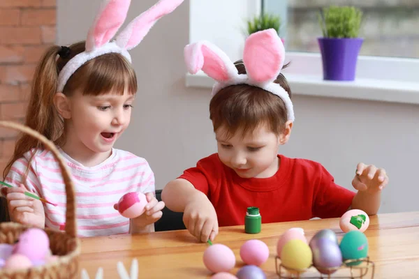 Petits enfants mignons peignant des œufs de Pâques à la maison — Photo