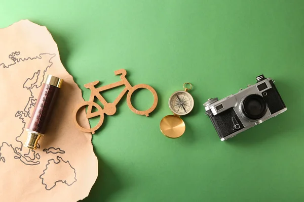 World map, spyglass, photo camera, compass and toy bicycle on color background. Travel concept — Stock Photo, Image