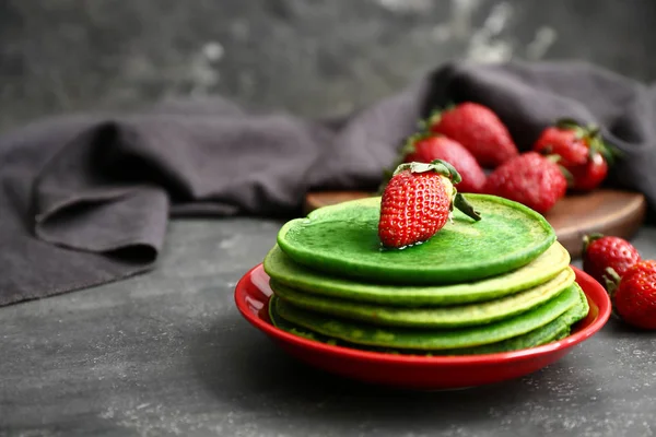 Тарелка с вкусными зелеными блинами на темном фоне — стоковое фото