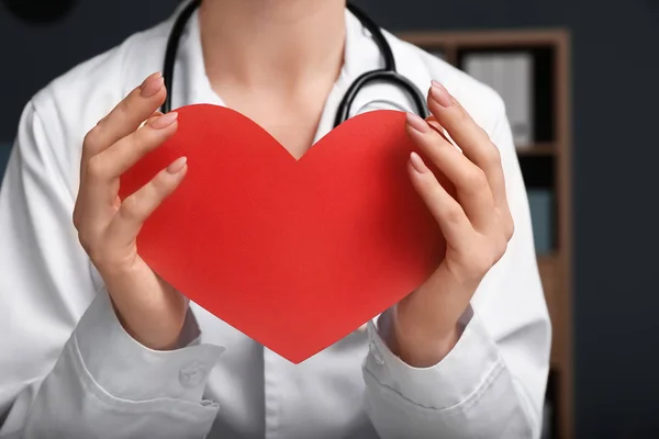 Cardiologista com coração vermelho na clínica, close-up — Fotografia de Stock