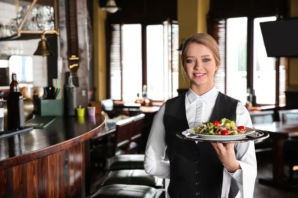 Młoda kobieta kelner z sałatką w restauracji — Zdjęcie stockowe